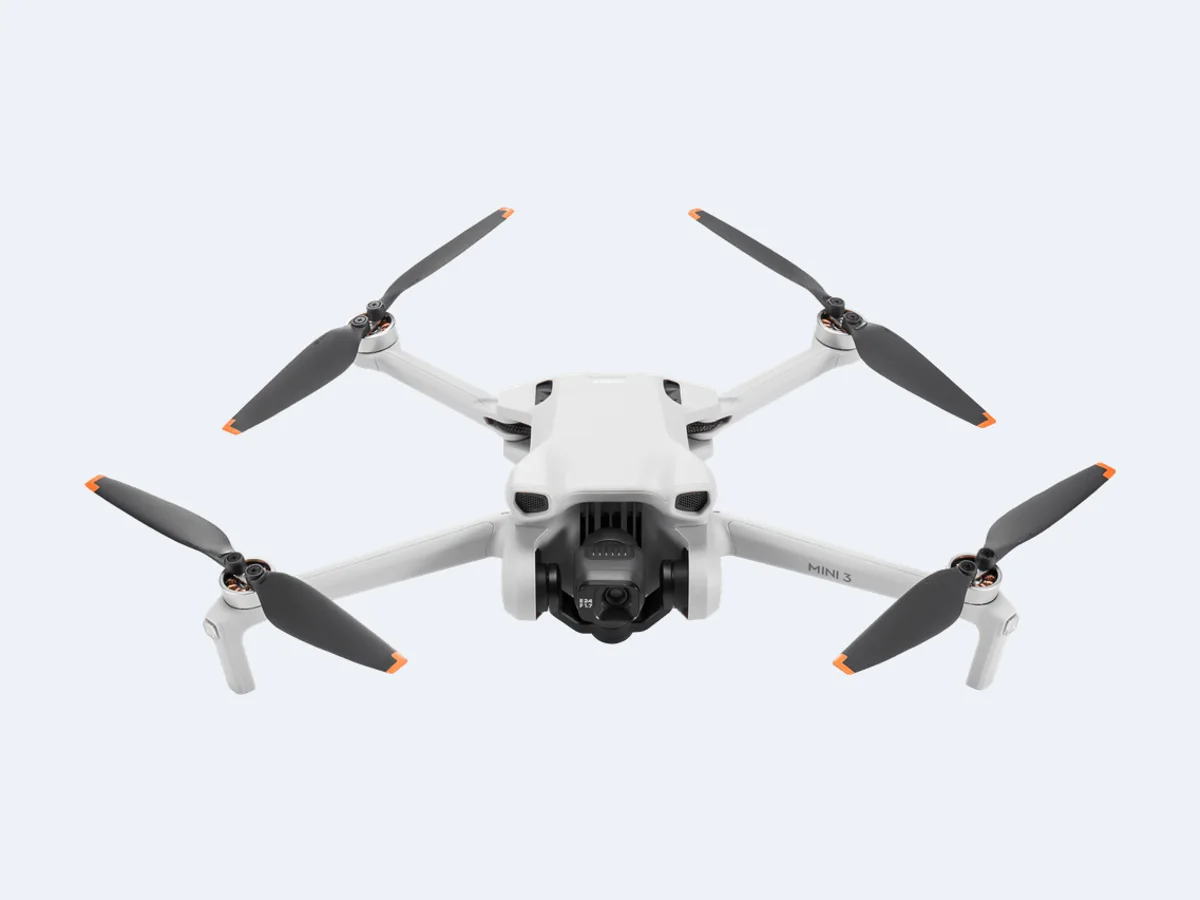 DJI Mini 3 visto de frente, com câmera sob o corpo e hélices abertas
