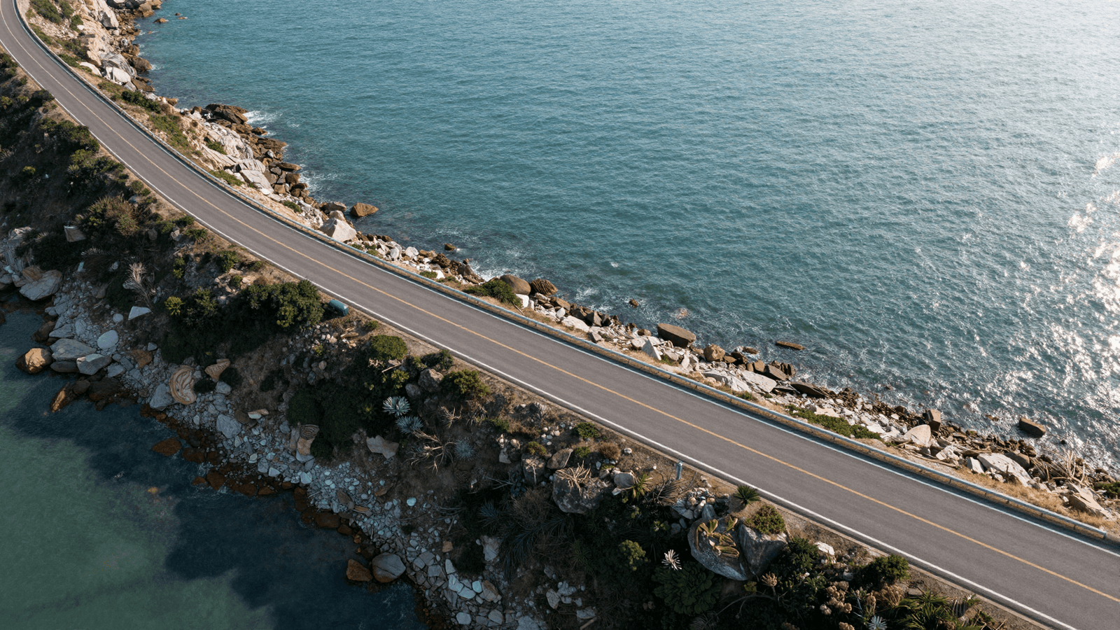 Vista aérea cenográfica de uma estrada sinuosa à beira-mar