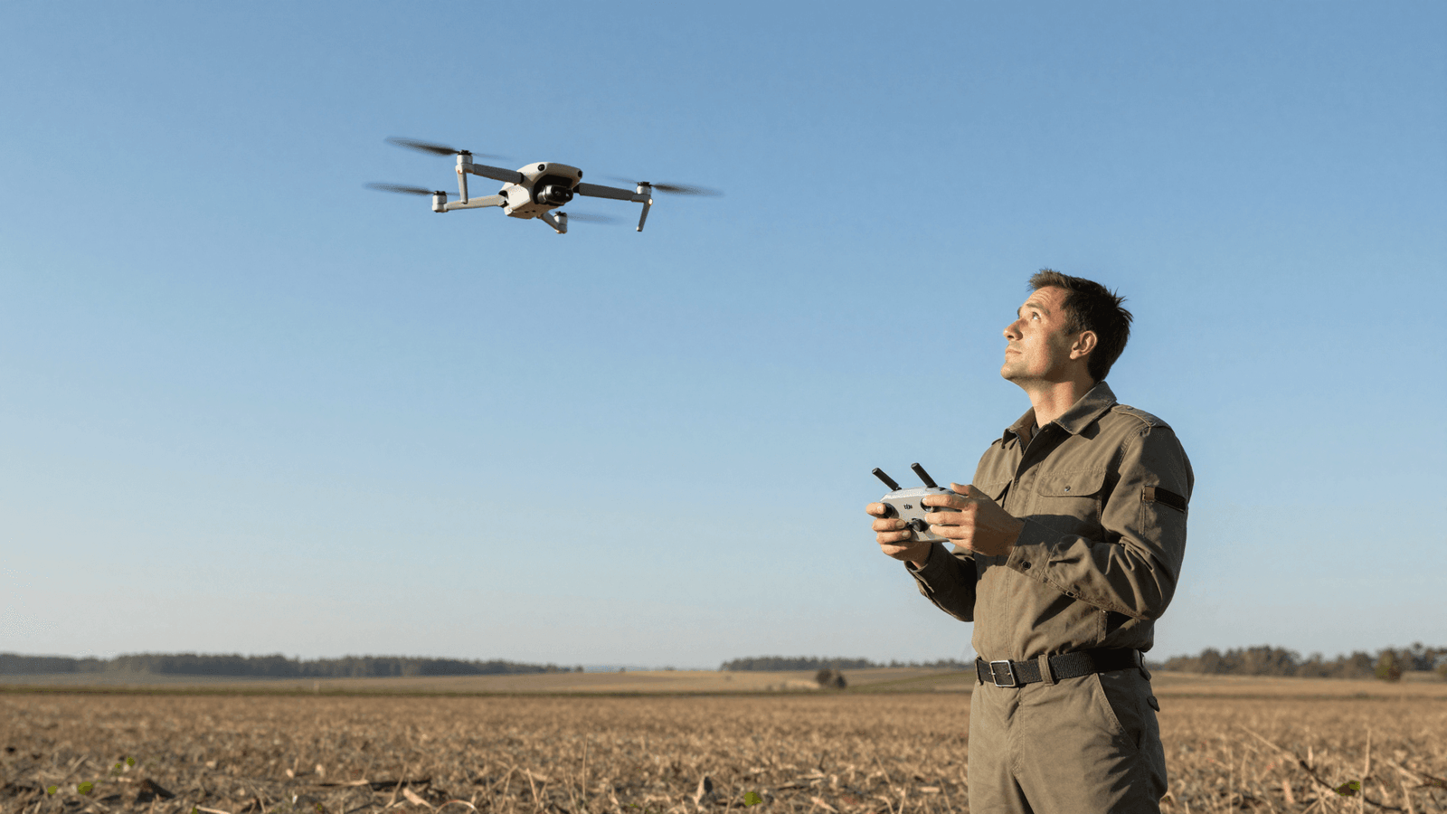 Piloto observando o espaço aéreo com o controle DJI em campo aberto