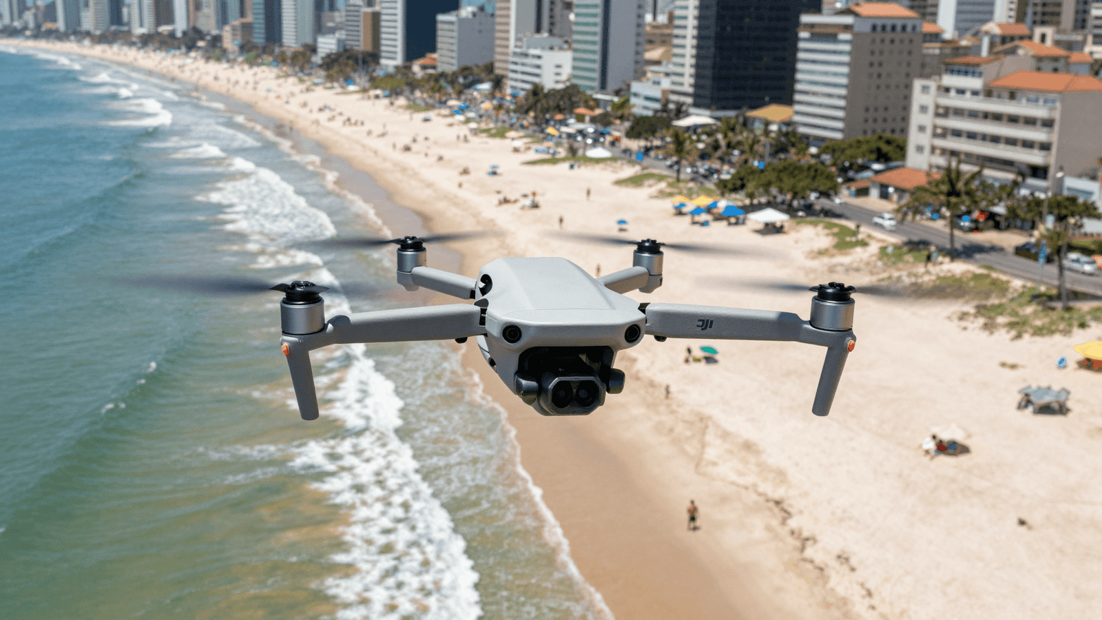 Drone DJI sobrevoando uma praia urbana movimentada no Brasil em dia ensolarado