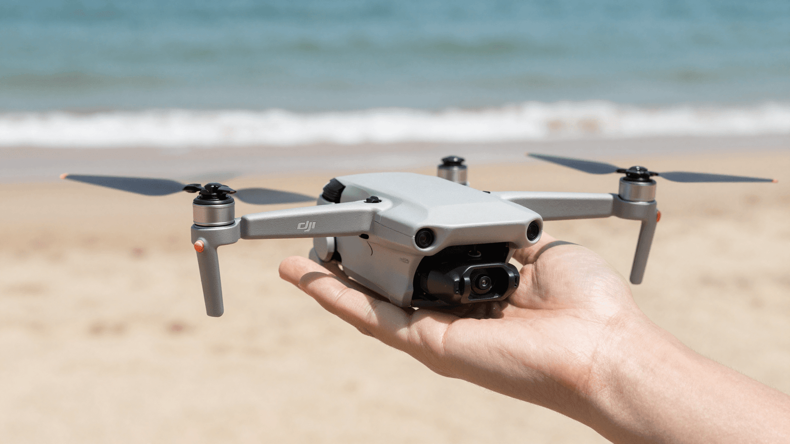 Piloto decolando um drone DJI Mini da palma da mão na areia da praia