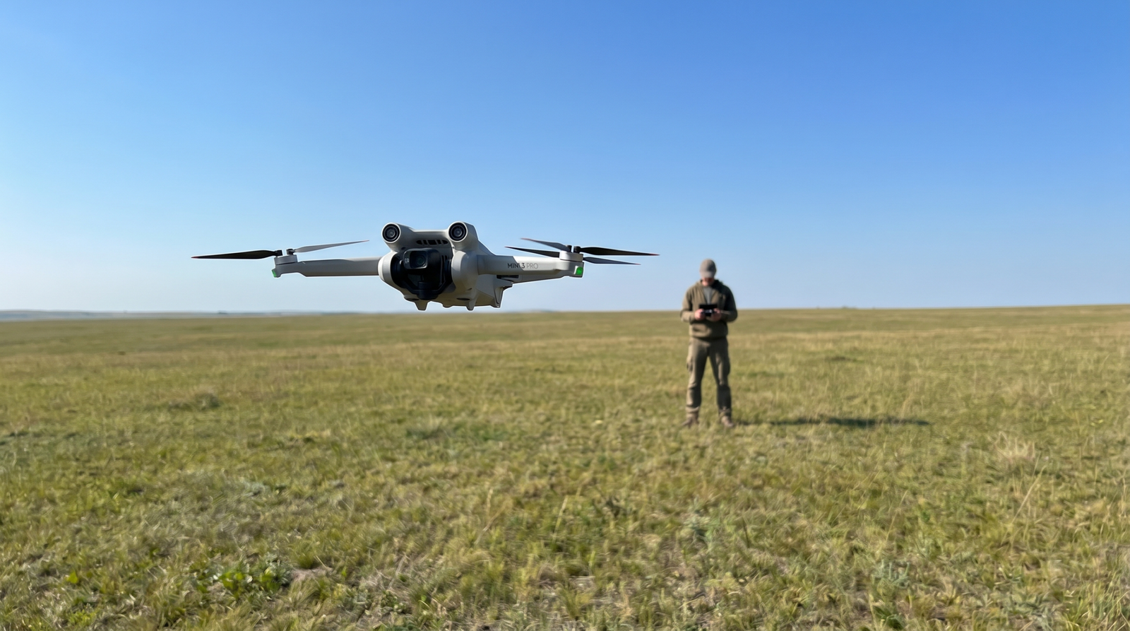 Drone voando baixo em campo aberto com o piloto observando a olho nu, dentro da categoria Aberta