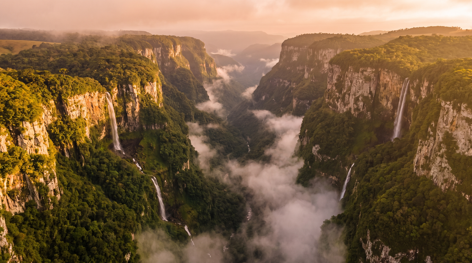 Foto aerea do Canion Itaimbezinho com paredoes verticais e mar de nuvens ao entardecer