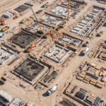 Vista aerea de um grande canteiro de obras com fundacoes e maquinas vistas de cima