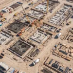 Vista aerea de um grande canteiro de obras com fundacoes e maquinas vistas de cima