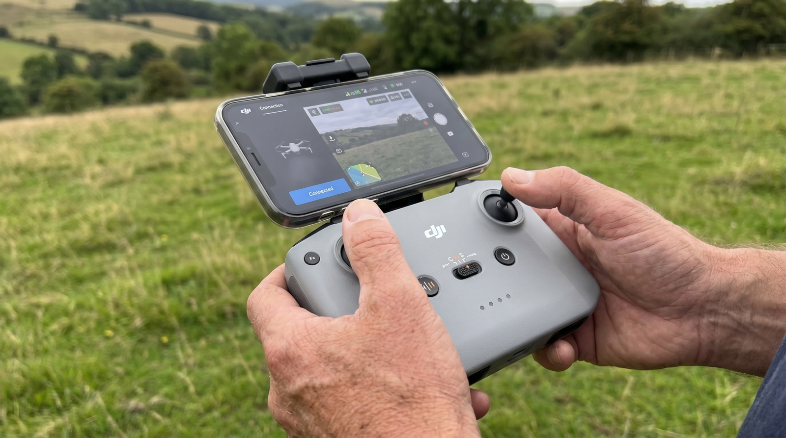 Maos segurando um controle de drone com o celular encaixado