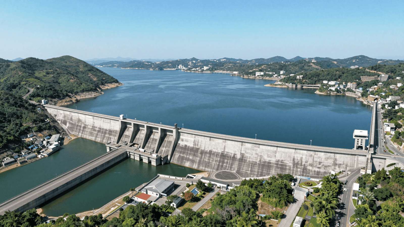Grande usina hidrelétrica e seu reservatório vistos do alto, área de infraestrutura crítica perto da fronteira