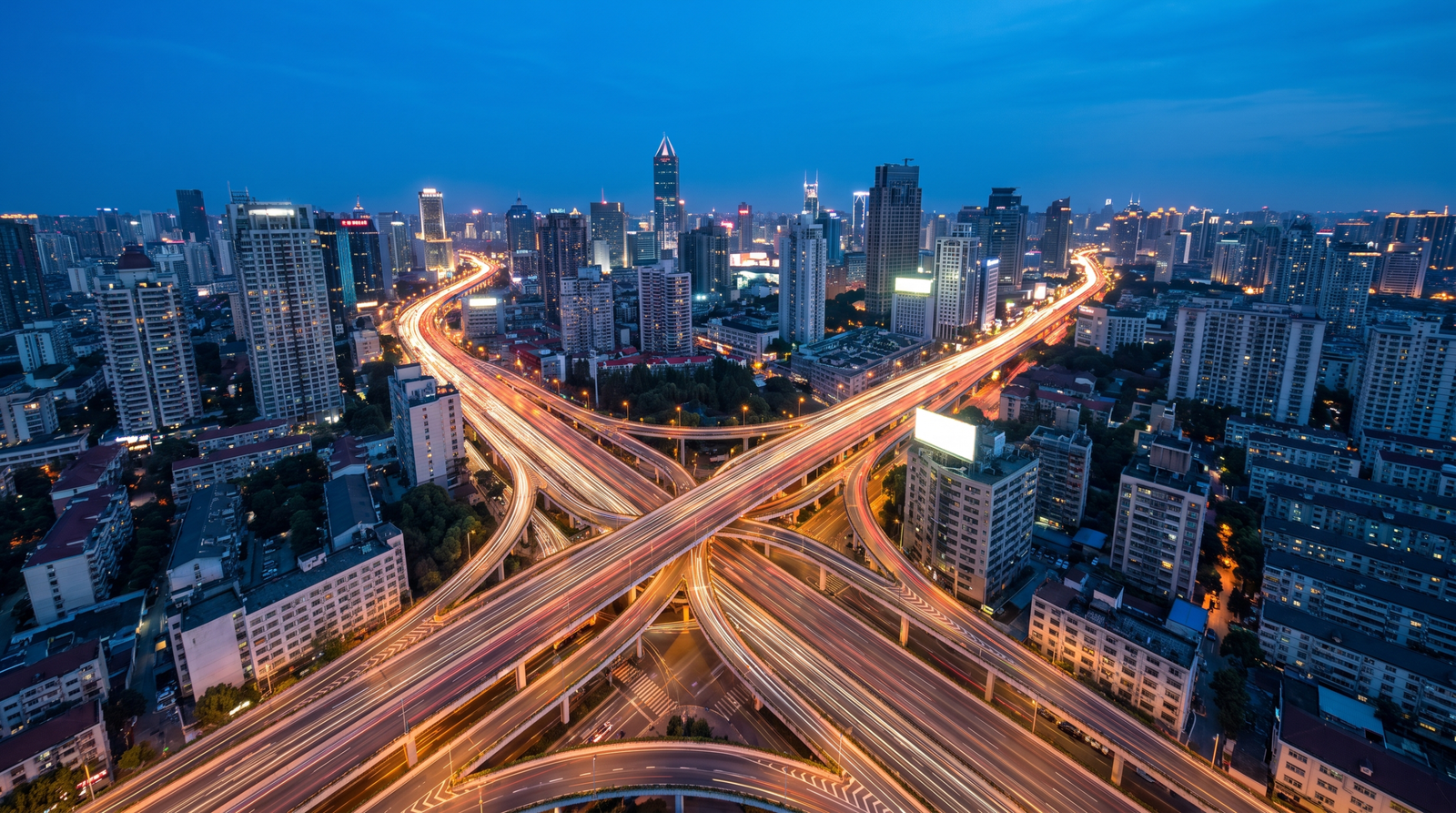 Foto aerea de uma cidade ao entardecer com rastros de luz nas avenidas na blue hour