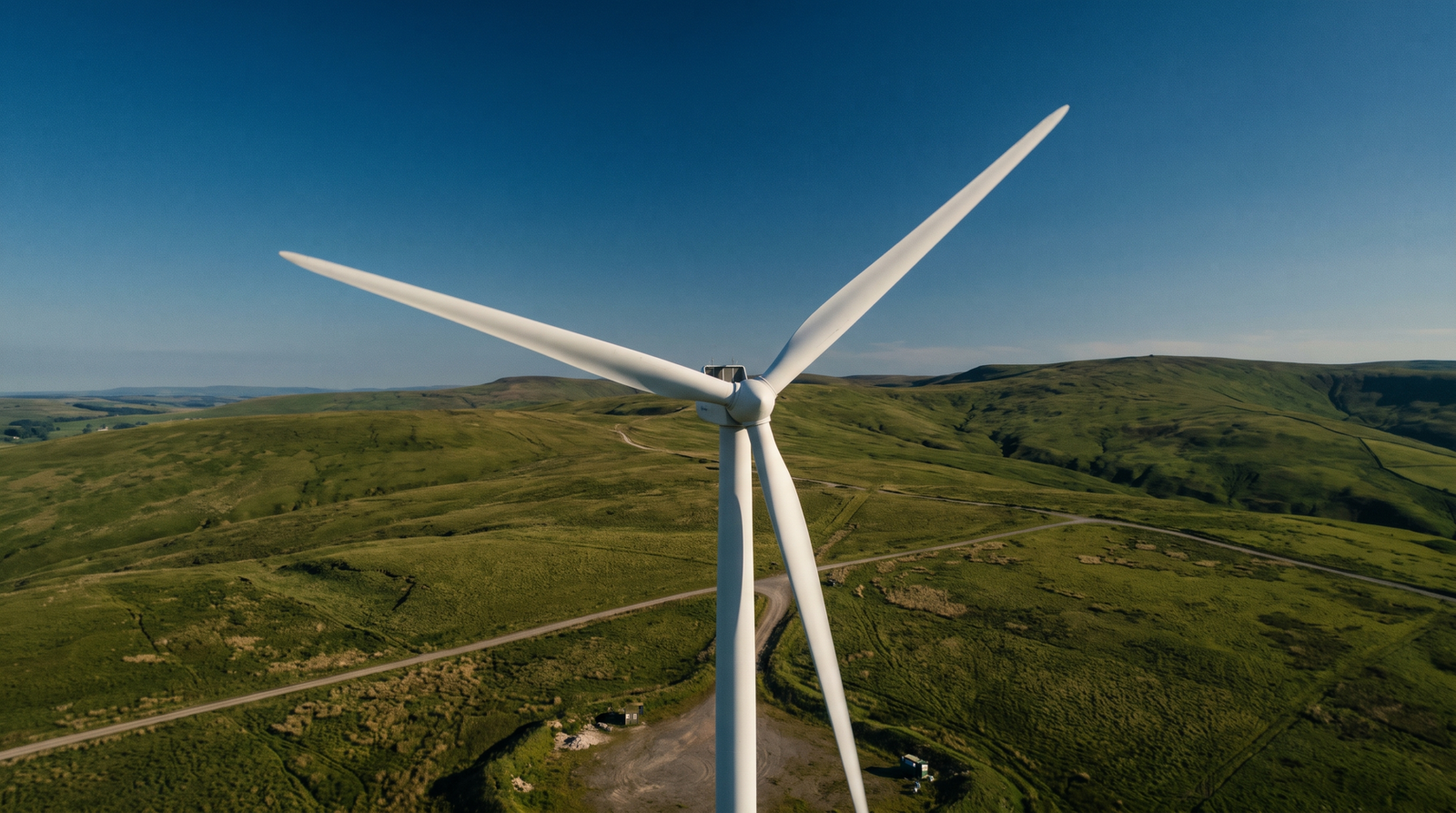 Foto aerea aproximada de uma turbina eolica branca e suas pas contra o ceu azul