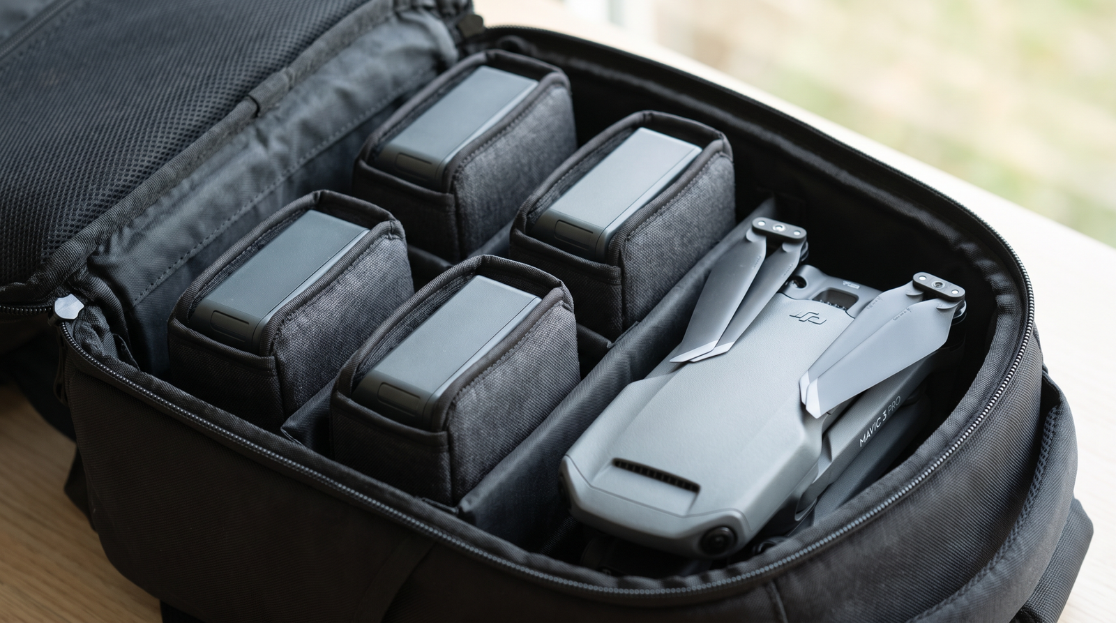 Baterias de drone protegidas em sacos individuais dentro de uma mochila de viagem com o drone ao lado