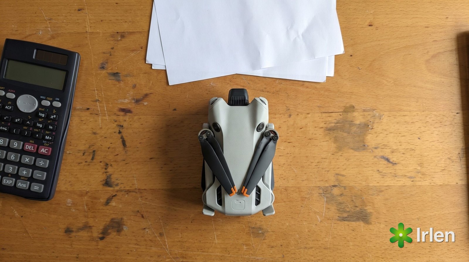 Calculadora, papéis e drone DJI Mini 4 Pro dobrado sobre a mesa