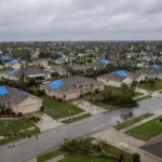 Vista aerea de um bairro residencial apos uma tempestade com telhados danificados