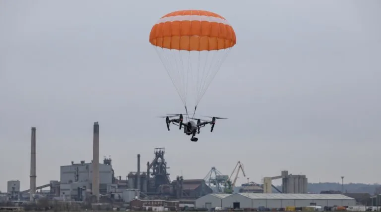 Drone profissional descendo suspenso por um paraquedas aberto