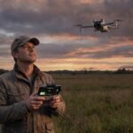 Piloto segurando o controle DJI corretamente, celular no suporte acima dos manches, olhando o drone no ceu