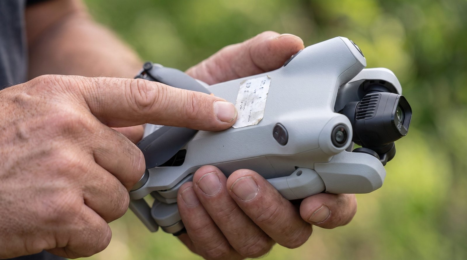 Mãos mostram a etiqueta de identificação colada no corpo do drone