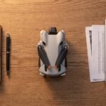 Mesa de trabalho com drone dobrado, documentos e notebook