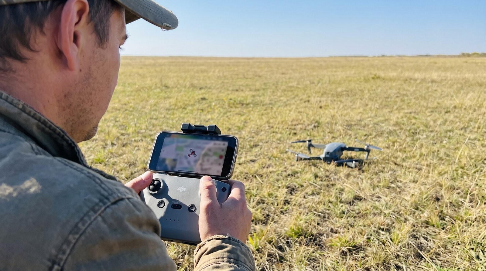 Piloto conferindo o sinal de GPS do drone no controle em campo aberto