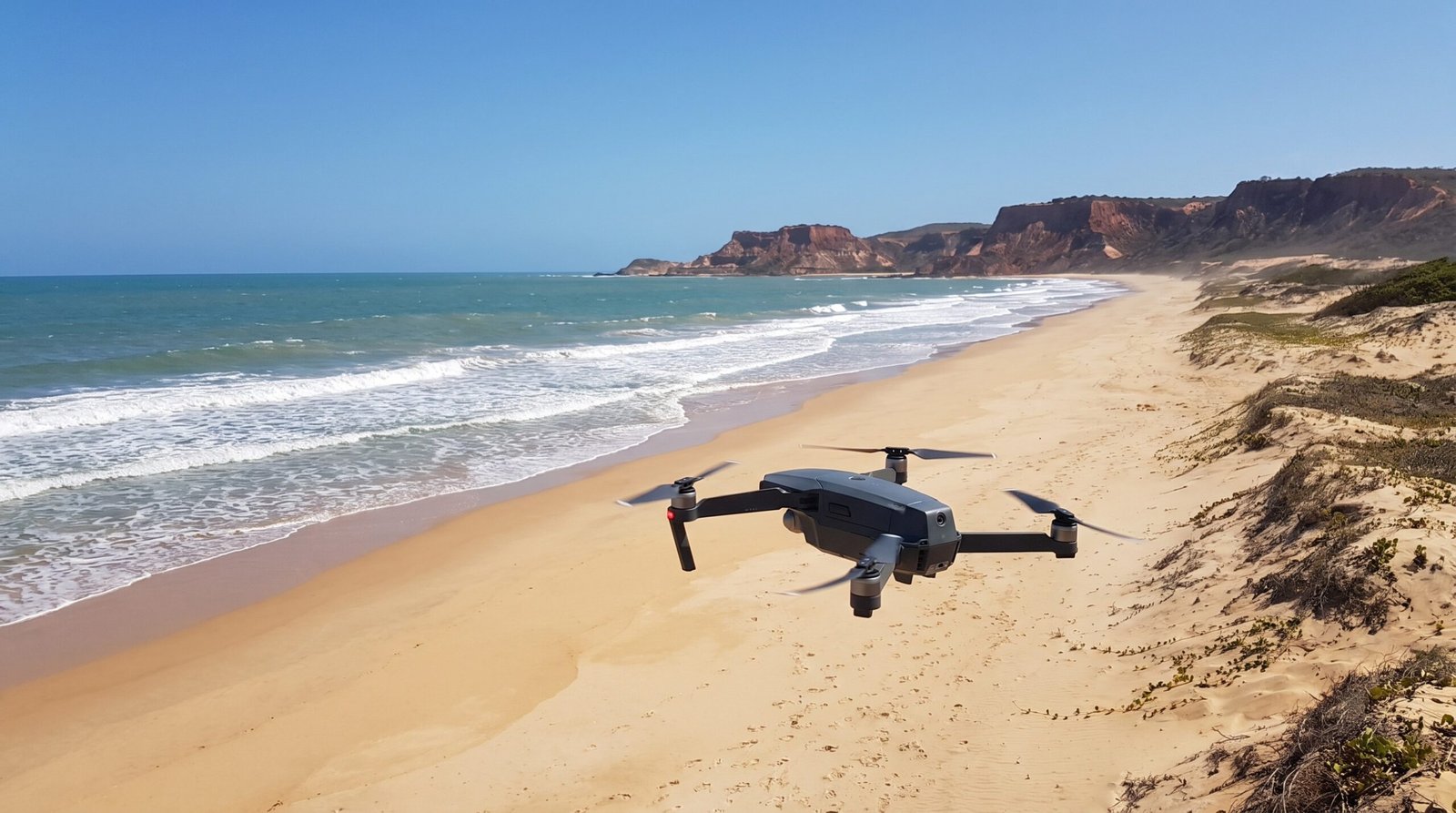 Drone DJI-style voando sobre um trecho vazio de praia no litoral do Ceara