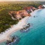 Vista aerea das falesias coloridas e do mar turquesa da Costa do Descobrimento ao entardecer