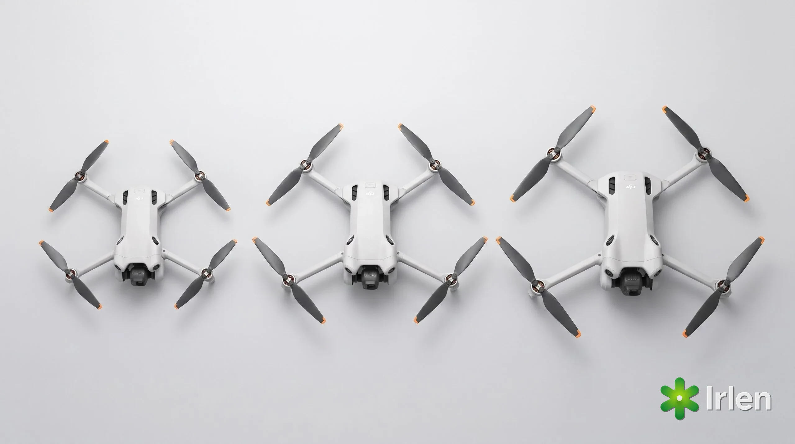 Três drones de tamanhos diferentes enfileirados sobre superfície clara