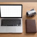 Mesa vista de cima com laptop, planilha em branco e um drone pequeno