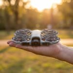 Drone DJI Neo 2 com gaiolas de hélice completas pousado na palma da mão
