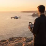 Piloto operando drone em falesia litoranea na hora dourada