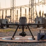 Drone industrial de grande porte pousado em plataforma diante de uma subestação