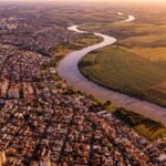 Vista aerea mostrando cidade densa de um lado e area agricola de outro