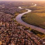 Vista aerea mostrando cidade densa de um lado e area agricola de outro