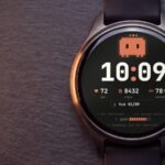 Watch face Claude Code acesa num relógio Garmin redondo AMOLED sobre ardósia escura