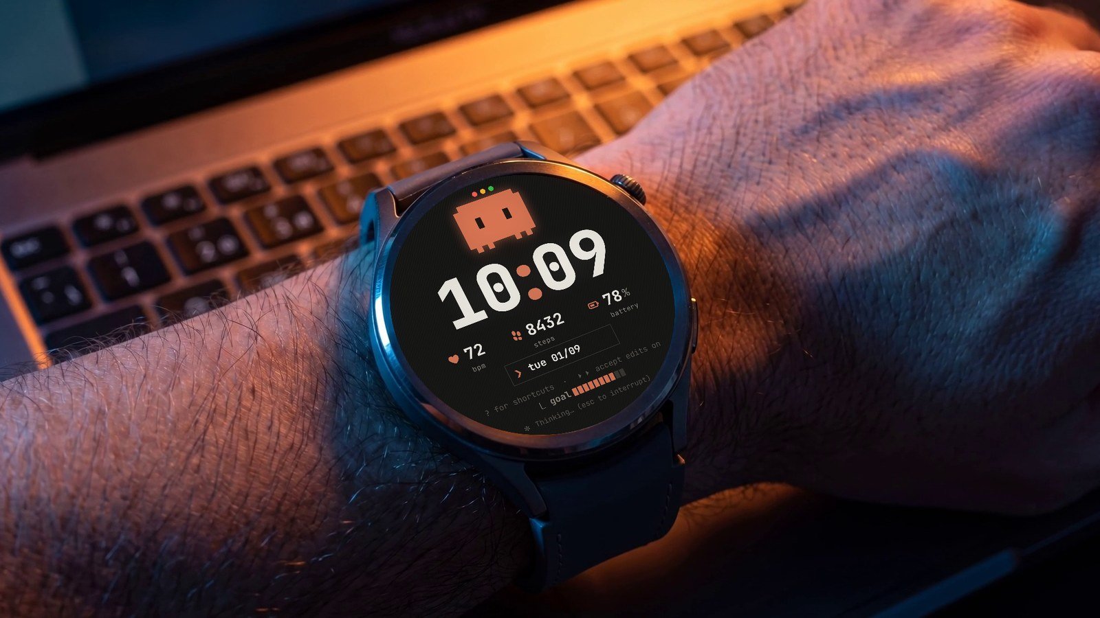 Relógio Garmin redondo no pulso, sobre o teclado do notebook, com a watch face Claude Code: Clawd, hora 10:09, batimentos, passos e bateria