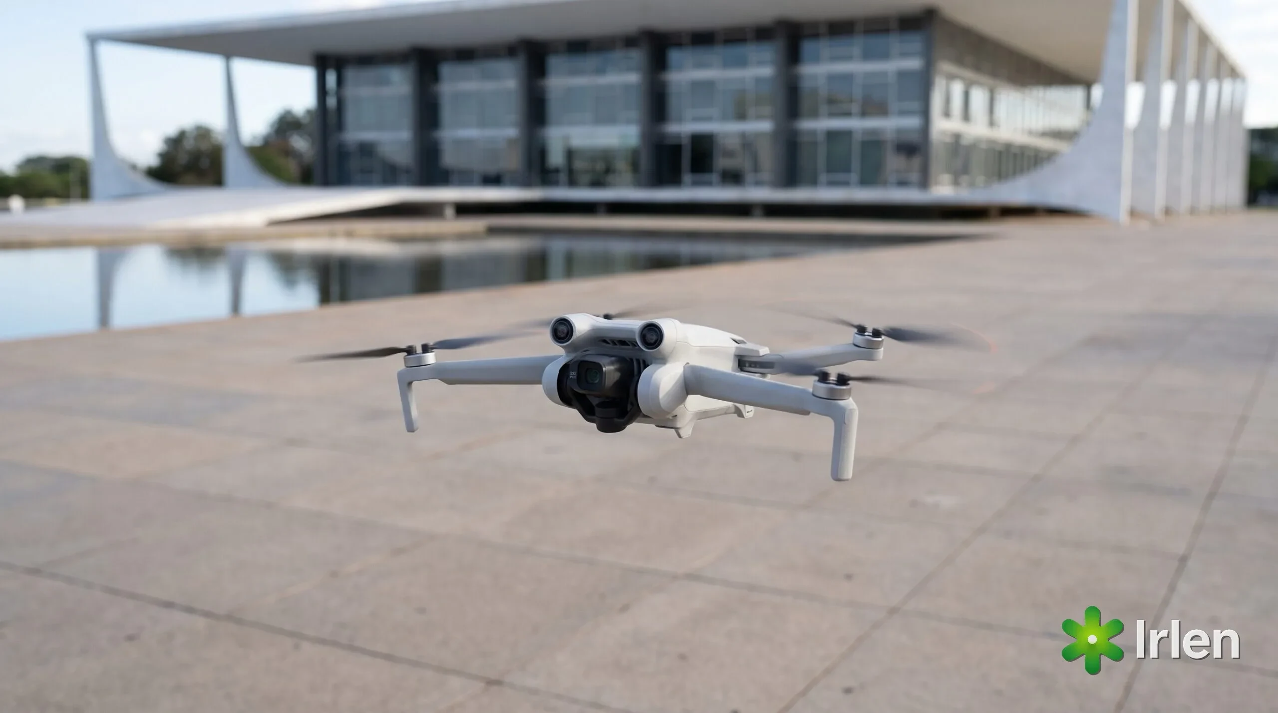 Drone pequeno descendo para pousar em uma praça com prédio modernista ao fundo