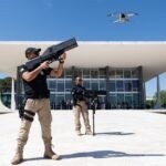 Agente da Polícia Judicial do STF aponta bloqueador antidrone para um drone sobre a Praça dos Três Poderes