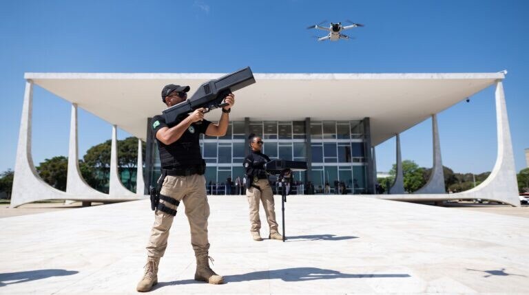 Agente da Polícia Judicial do STF aponta bloqueador antidrone para um drone sobre a Praça dos Três Poderes