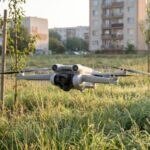 Drone pairando baixo sobre um terreno urbano com mato alto