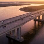 Ponte rodoviária de concreto cruzando um rio largo ao entardecer