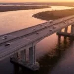 Ponte rodoviária de concreto cruzando um rio largo ao entardecer