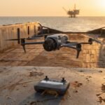 Drone paira sobre o convés de um navio com uma plataforma de petróleo no horizonte