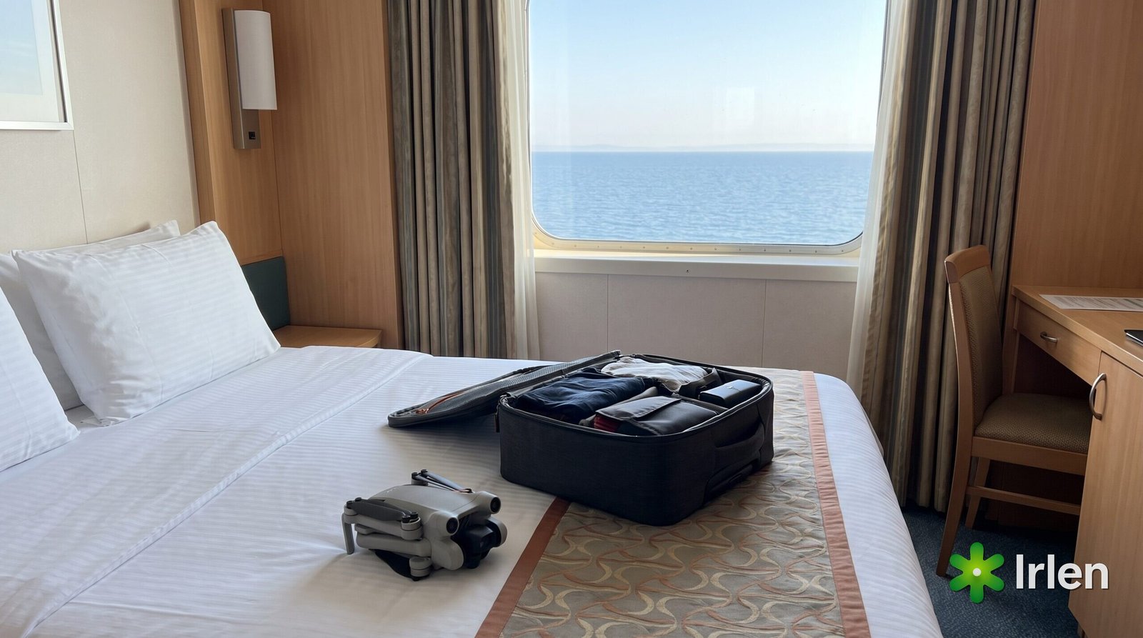 Drone dobrado sobre a cama de uma cabine de cruzeiro com mala aberta