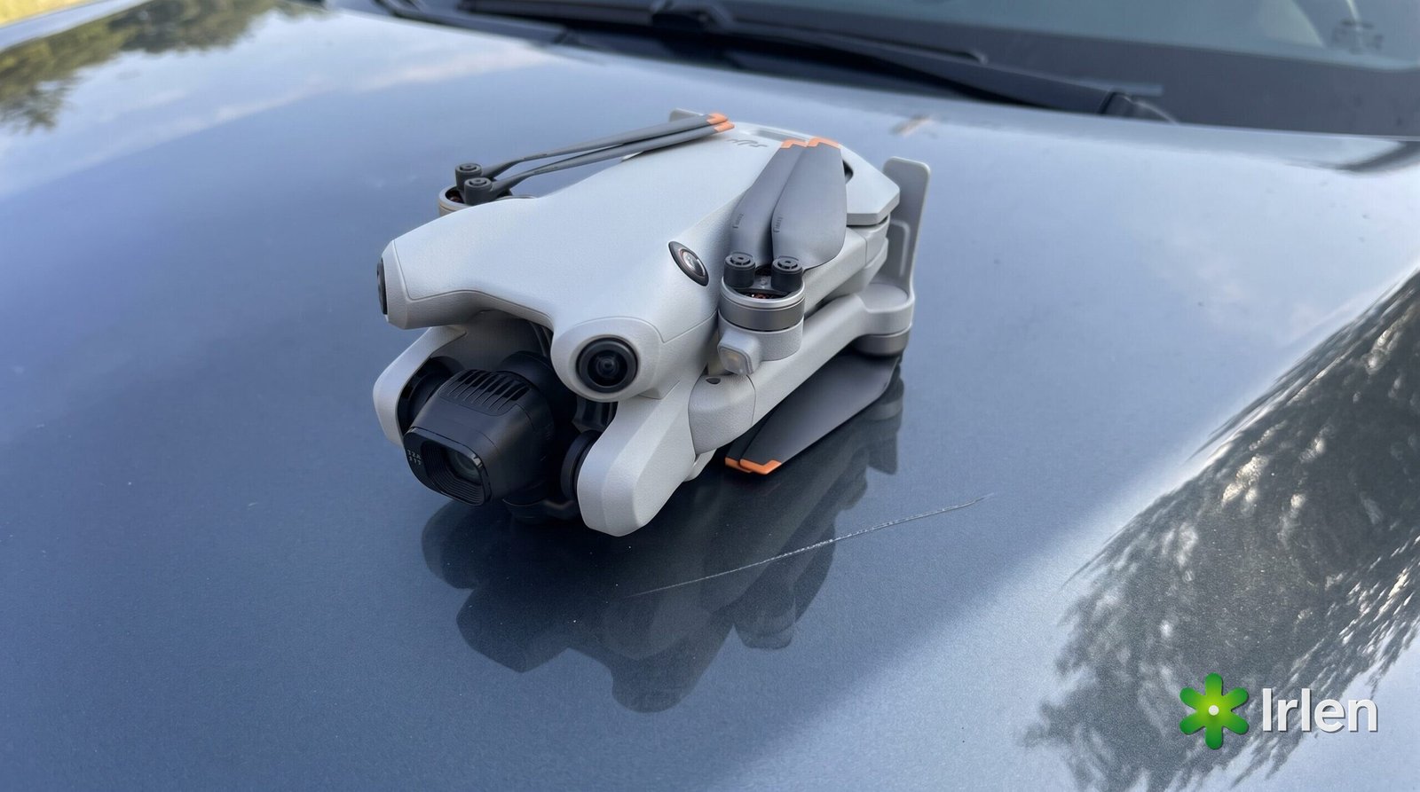 Drone dobrado sobre o capô de um carro com um risco na pintura