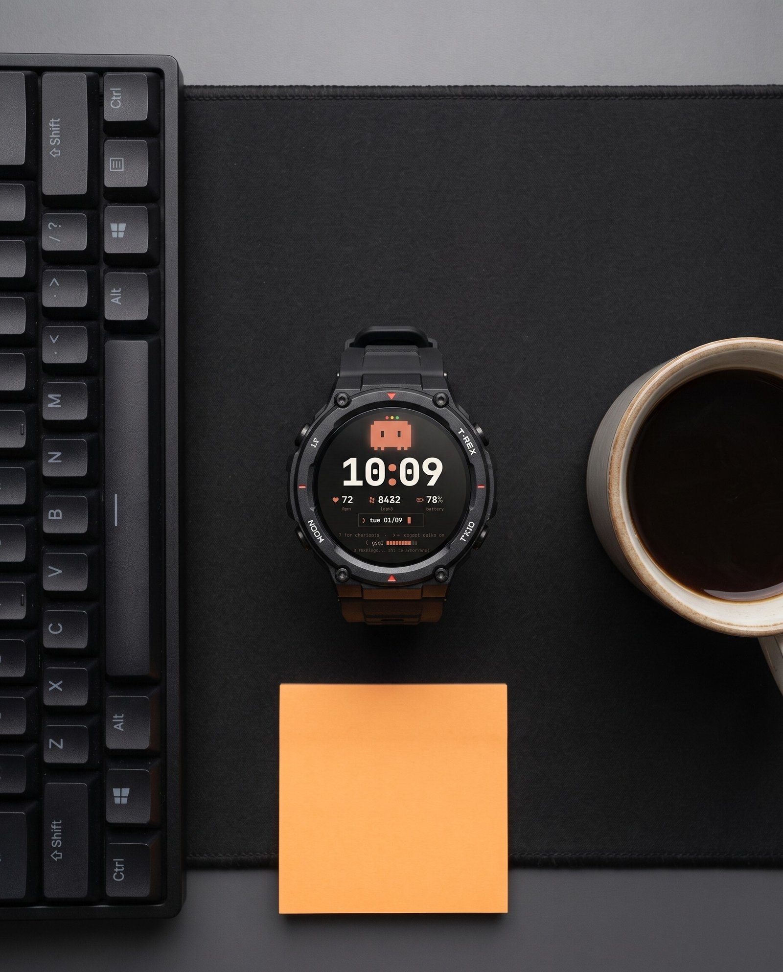 Amazfit T-Rex 3 com a watch face Claude Code sobre a mesa, ao lado de teclado e caneca