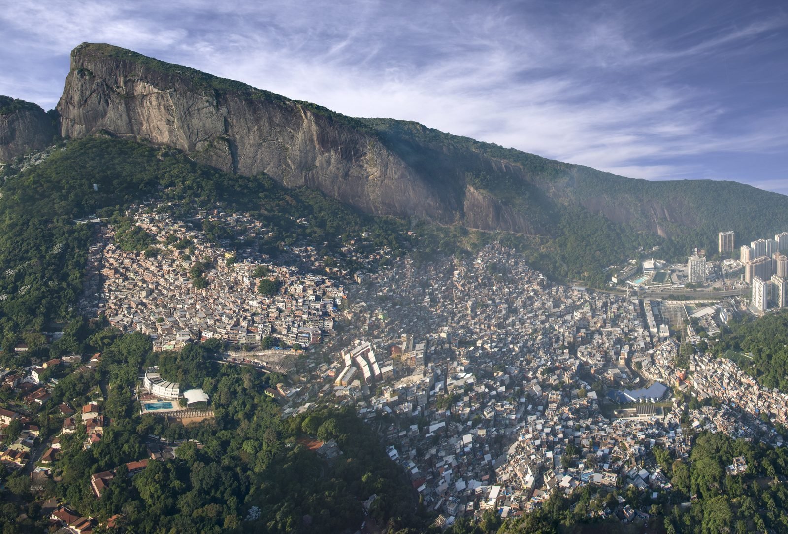 Vista aérea da Rocinha, no Rio de Janeiro, com o casario subindo o morro e o mar ao fundo