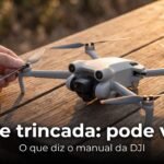 DJI Mini 5 Pro sobre uma mesa de madeira, com a mão de um piloto segurando a ponta de uma hélice para inspeção