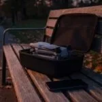 Drone DJI Air 3S usado dentro de um case aberto sobre um banco de praça ao entardecer