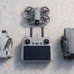 Controle DJI RC 2 sobre uma mesa ao lado dos drones DJI Mini 4 Pro, Air 3S e Neo 2