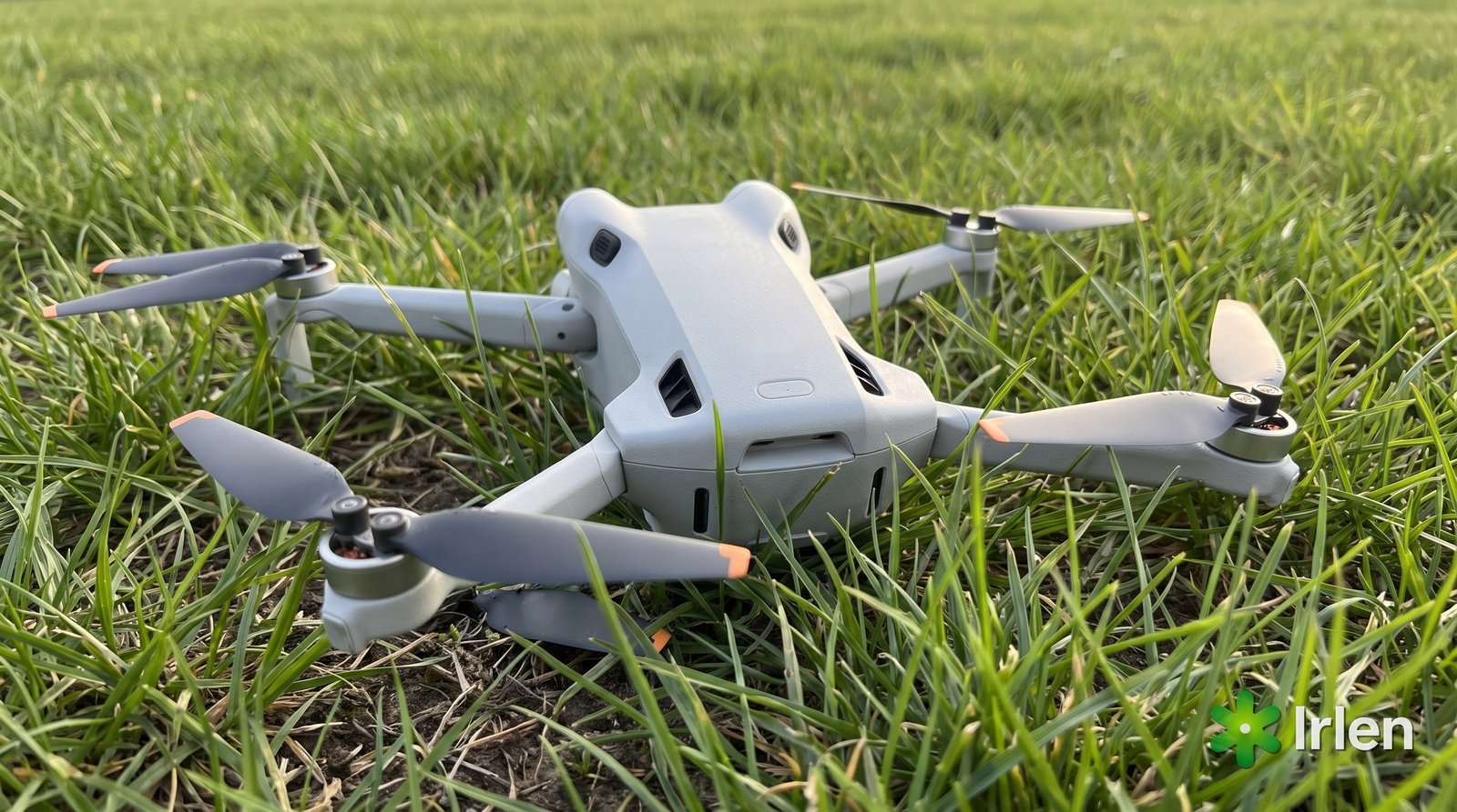 Drone DJI Mini 4 Pro caído na grama com uma hélice quebrada ao lado