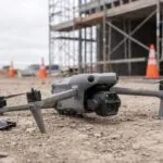 Drone DJI Air 3S caído no chão de um canteiro de obras com uma hélice quebrada