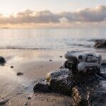 Drone DJI Mini 4 Pro pousado numa pedra na beira de uma praia ao nascer do sol