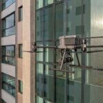 Drone DJI Matrice 350 RTK parado perto da fachada de vidro de um prédio residencial